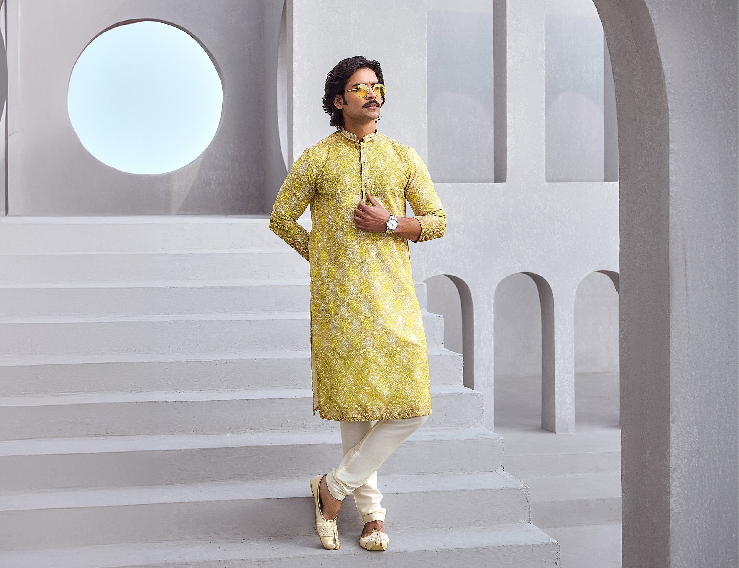 A man dressed in a vibrant yellow floral kurta and pajama set, ideal for a casual groom's attire.